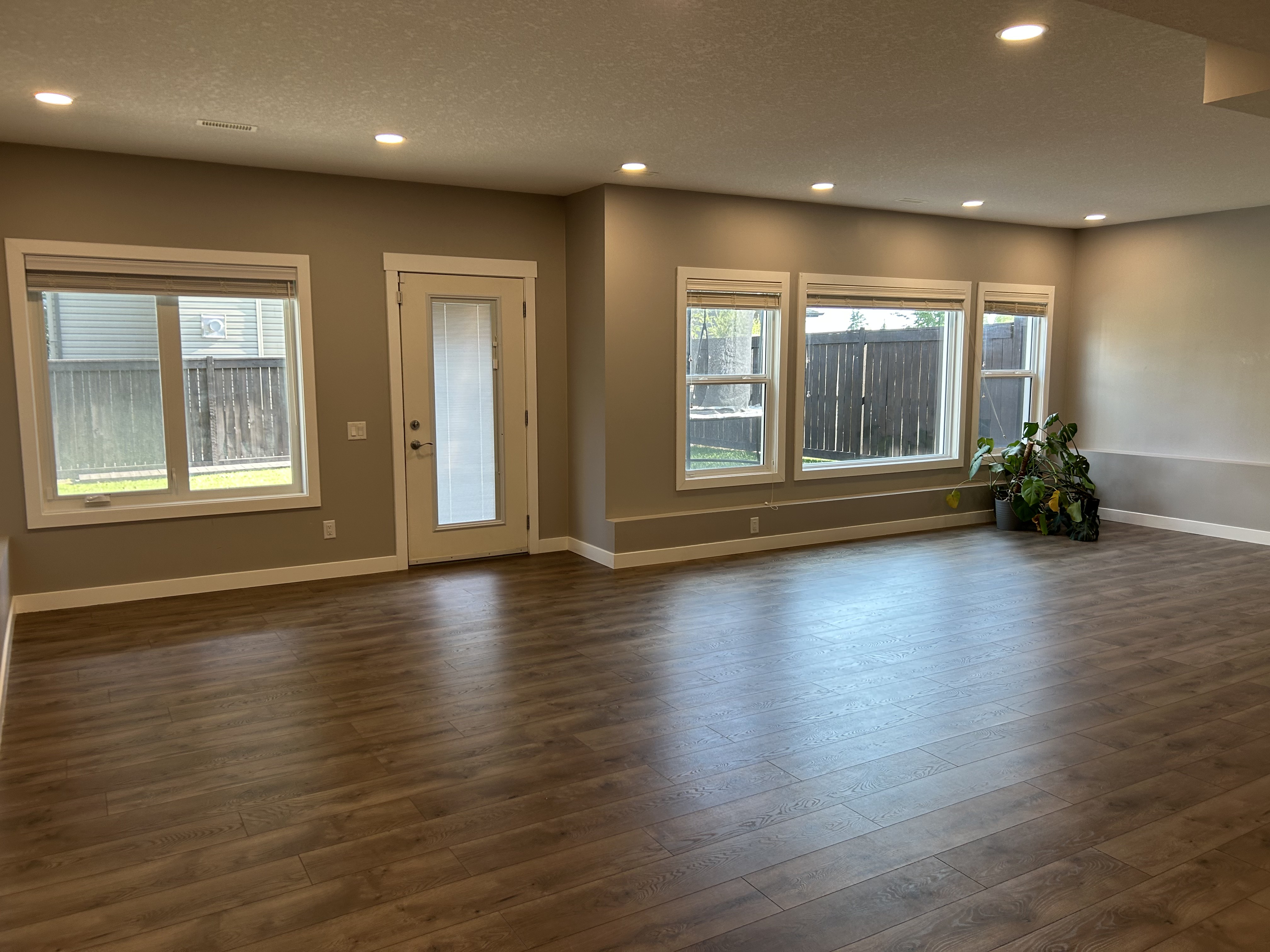 A clean, empty room with wood flooring and wide windows, ready for its next chapter